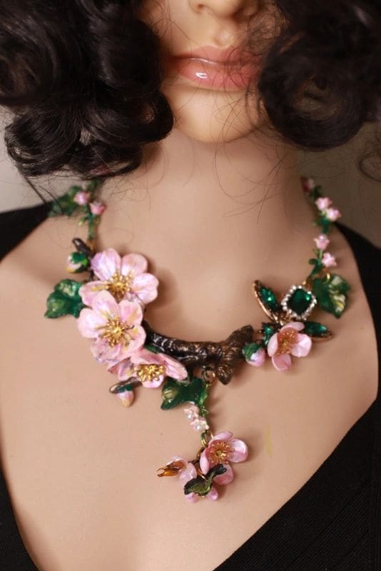 A woman wearing a necklace with pink flowers.