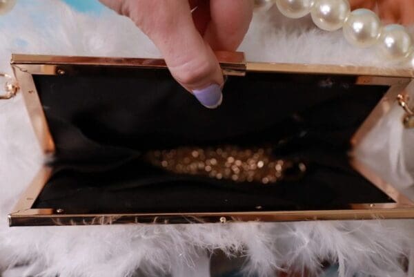 A person opening up an open box with jewelry inside.