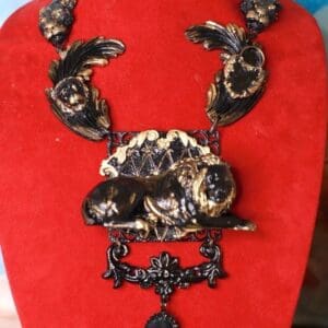 A red velvet display case with a black and gold necklace.