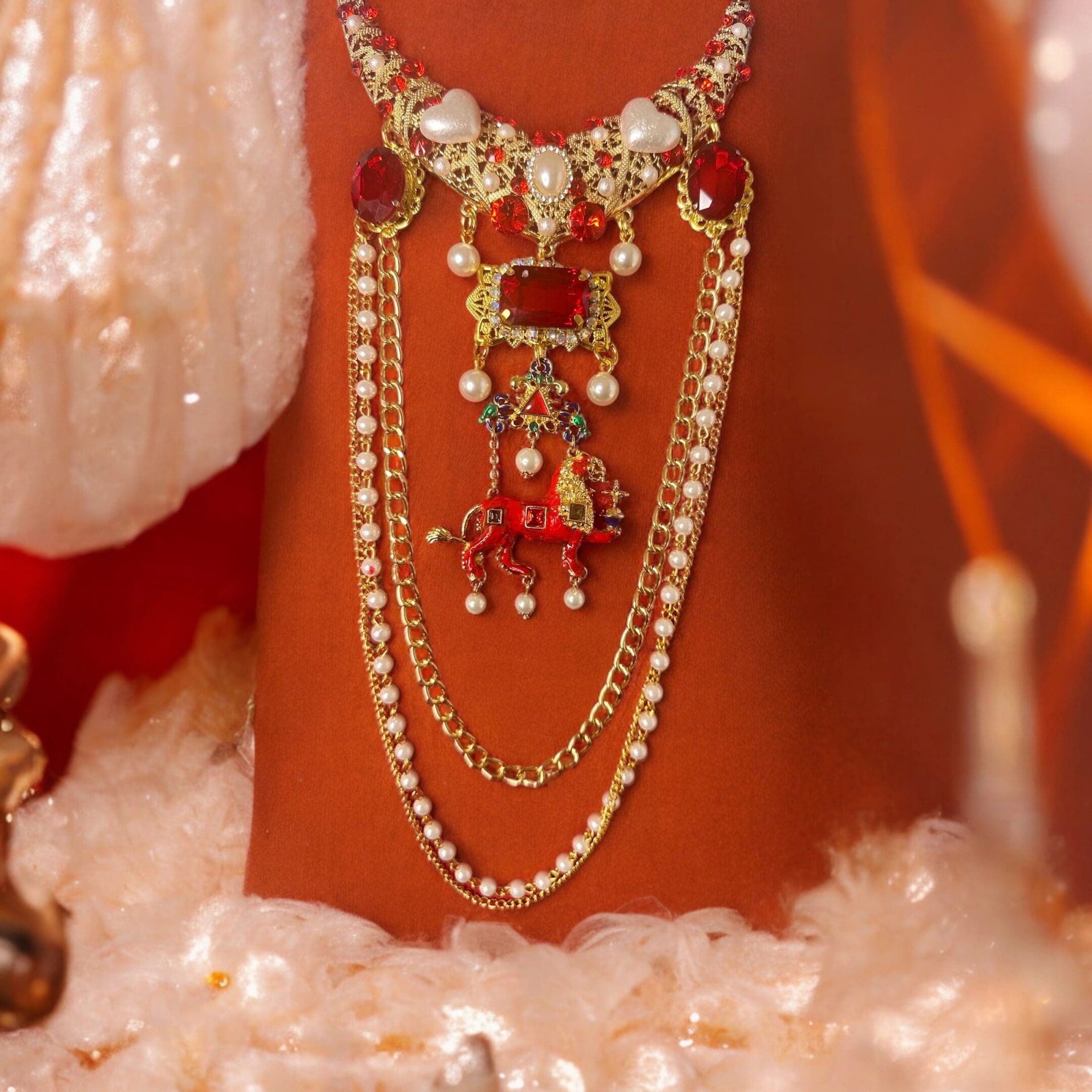 A necklace with pearls and red stones on it.