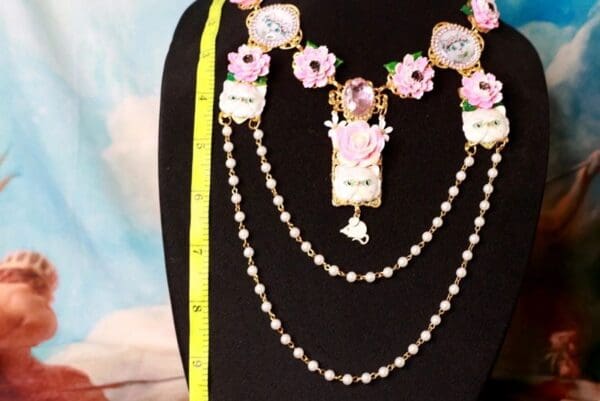 A black mannequin with pink flowers and pearls.