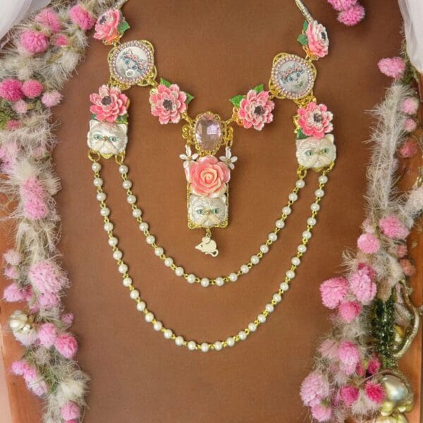 A woman wearing a necklace with pink flowers.