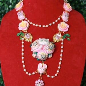 A red display stand with a necklace and cat brooch.