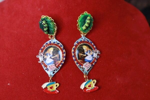 A pair of earrings with pictures and leaves on them.