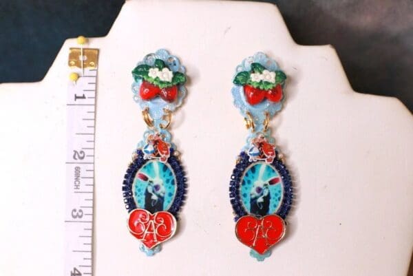 A pair of earrings with a cat and heart on them.