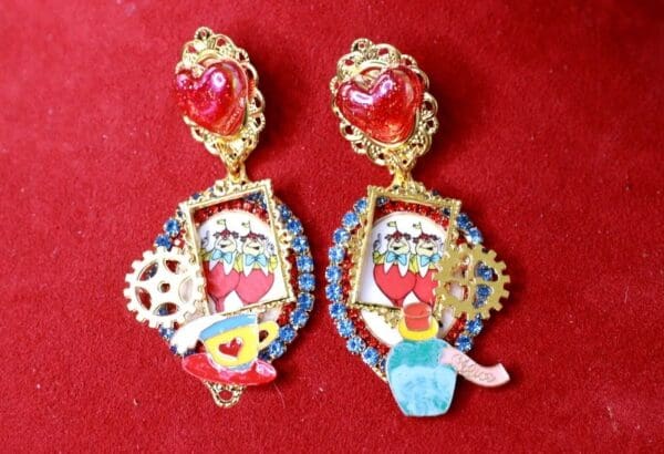 A pair of earrings with red hearts and pictures.