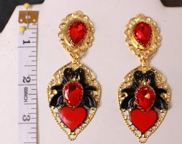 A pair of earrings with red and black designs.