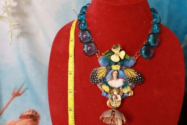A red mannequin wearing a necklace with various colorful jewelry.