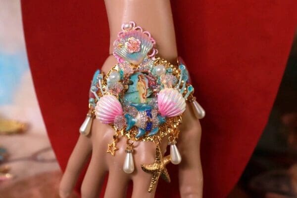 A hand with a bracelet and some shells on it