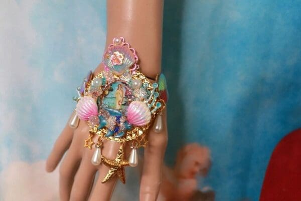 A hand with a bracelet and some shells on it