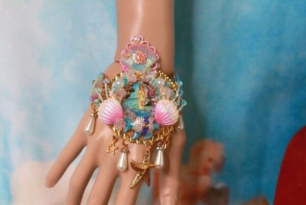 A hand with a bracelet and some shells on it