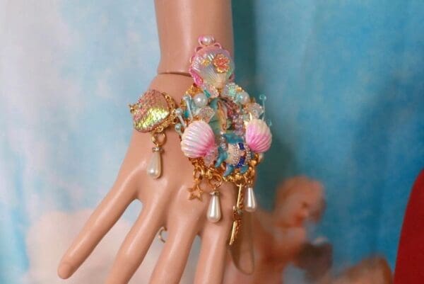 A hand with a bracelet and earrings on it