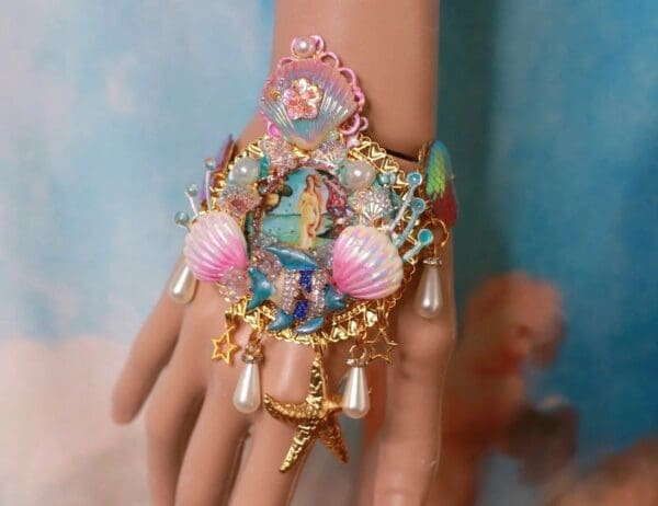 A hand with a bracelet and some shells on it