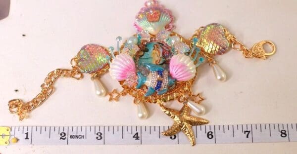 A gold chain with a pink and blue shell charm.