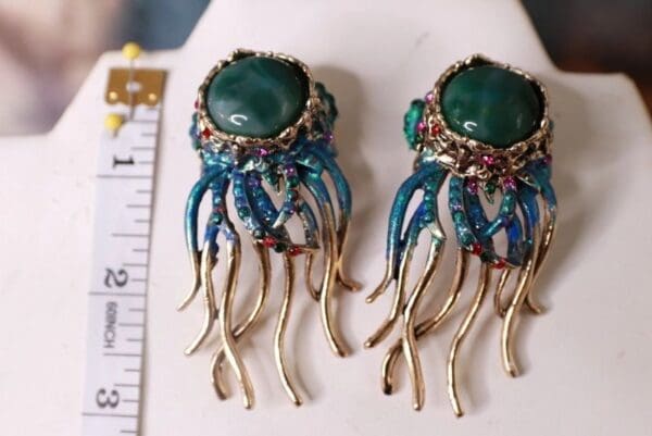 A pair of earrings with green stones and blue beads.