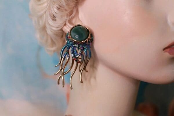 A woman wearing earrings with blue and green accents.