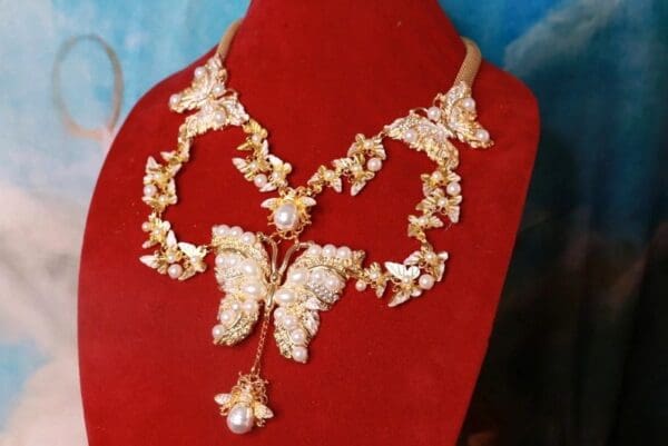 A red velvet display with a butterfly necklace.