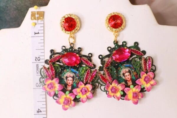 A pair of earrings with flowers and a woman 's face.