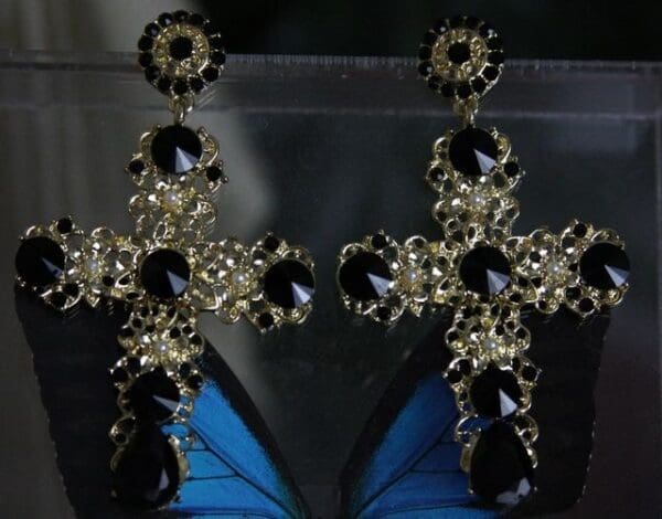 A pair of black and silver earrings on top of a butterfly.