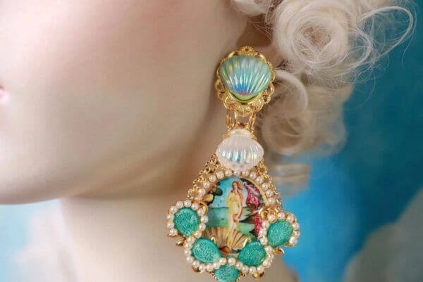 A woman wearing a pair of earrings with pearls and turquoise.