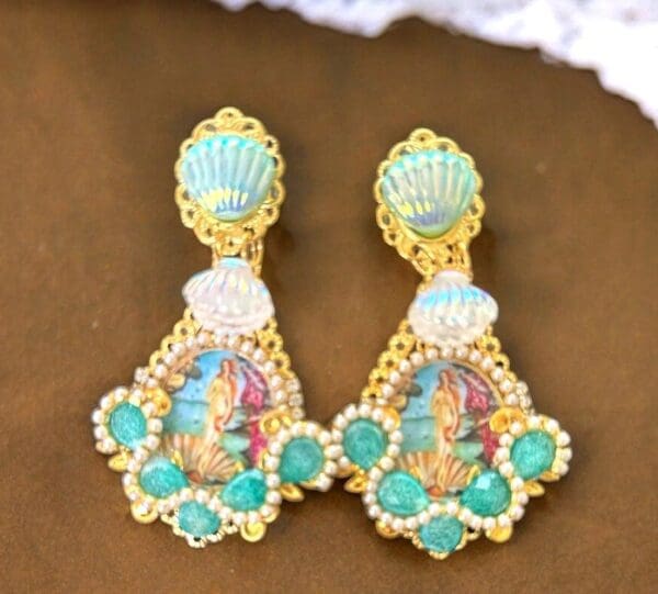 A pair of earrings with shells and an image of the sea.