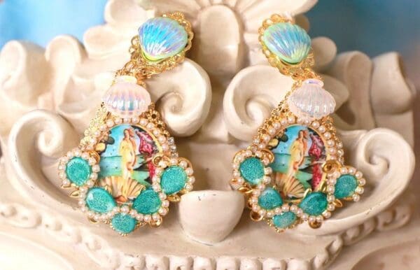 A pair of earrings with shells and flowers on top of it.