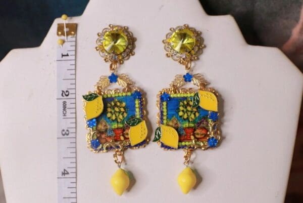 A pair of earrings with lemons and other things on them