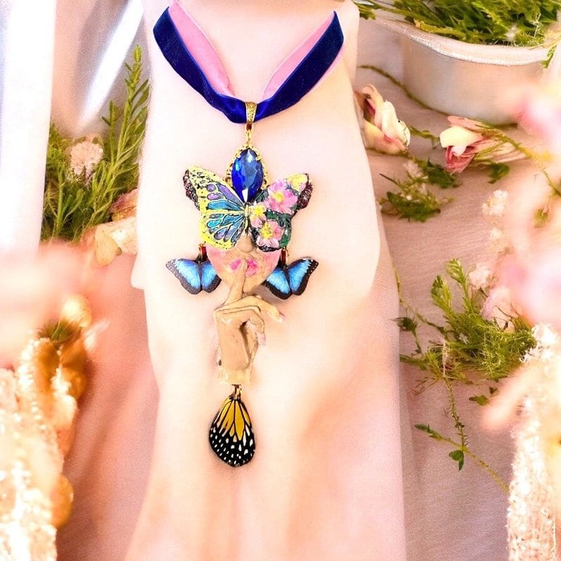 A woman wearing a necklace with a butterfly on it.