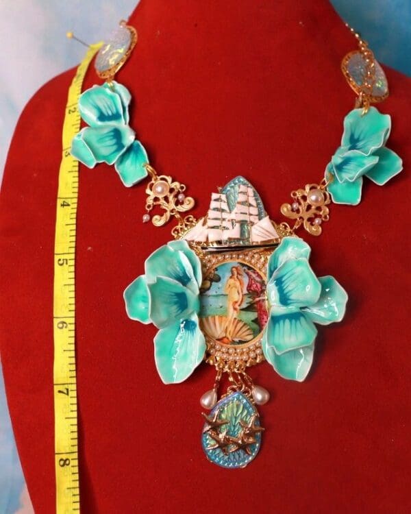 A necklace with blue flowers and a ship on it.