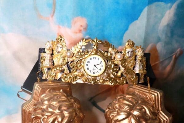 A gold clock with angels on it and two golden shoes