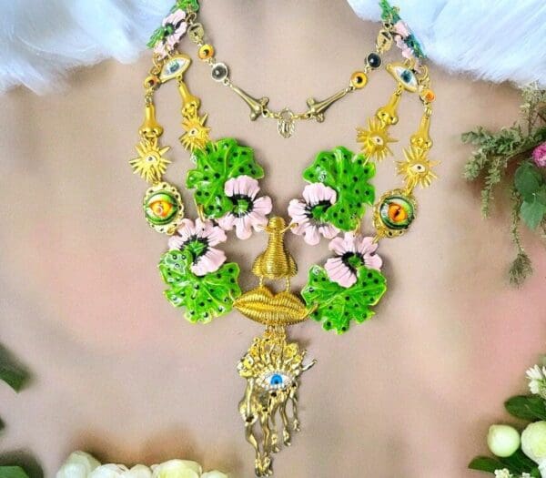 A woman wearing a necklace with green flowers and gold accents.