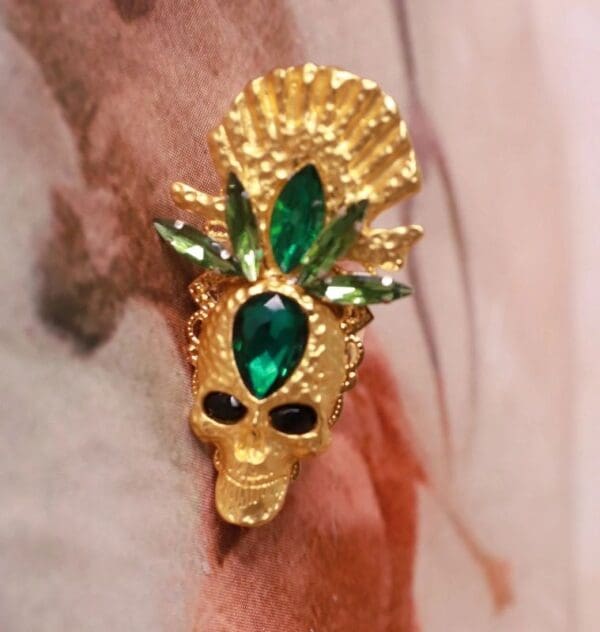 A gold skull with green eyes and a crown.