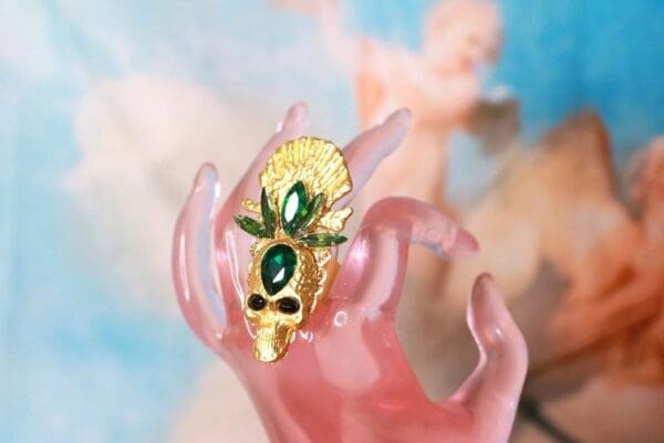 A hand holding something with a green stone on it.