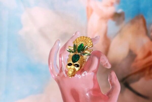 A pink hand with a gold mask on it
