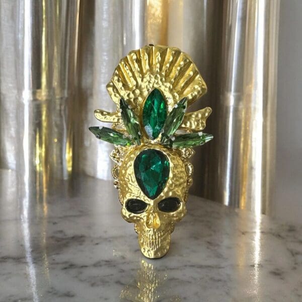 A gold skull with green eyes and a crown.