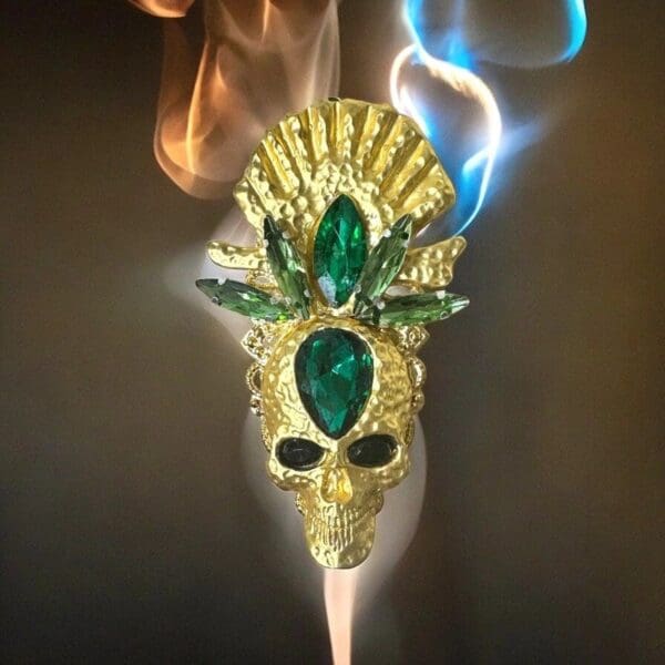 A gold mask with green jewels on it.