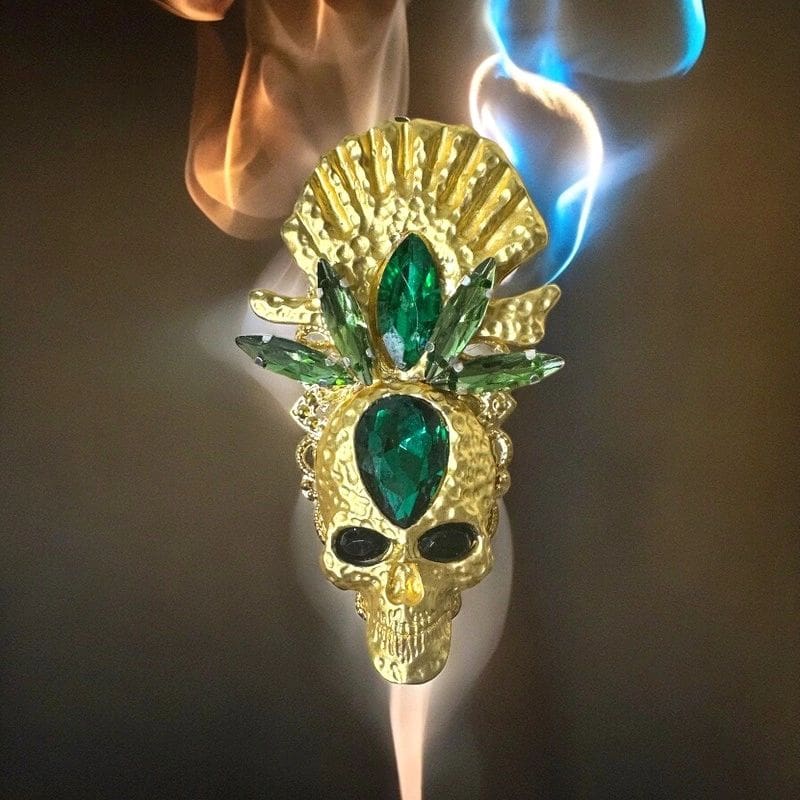 A gold mask with green jewels on it.