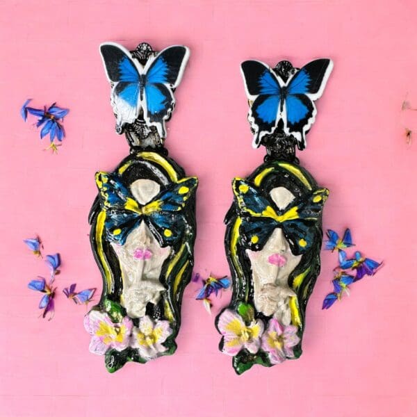 A pair of earrings with butterflies and flowers on them.