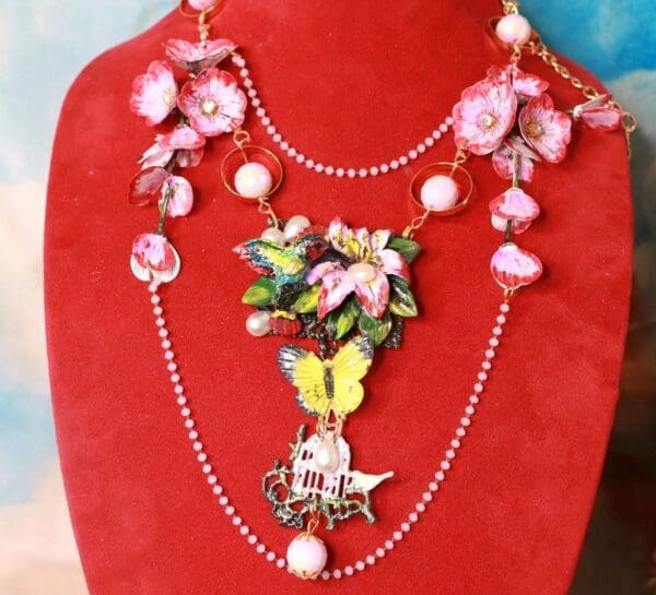 A red display stand with a necklace and some flowers