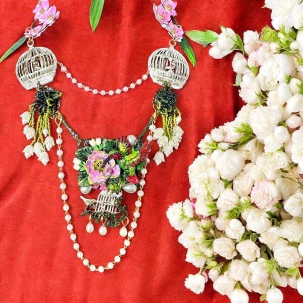 A necklace with flowers and pearls on the neck.