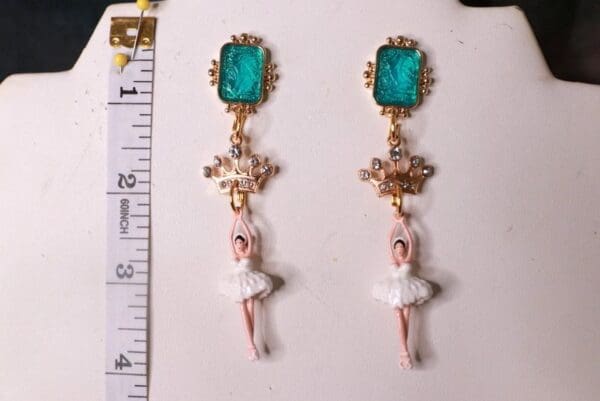 A pair of earrings with a ballerina and a cross.