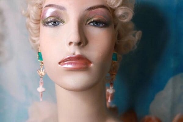 A mannequin with pink and green earrings.