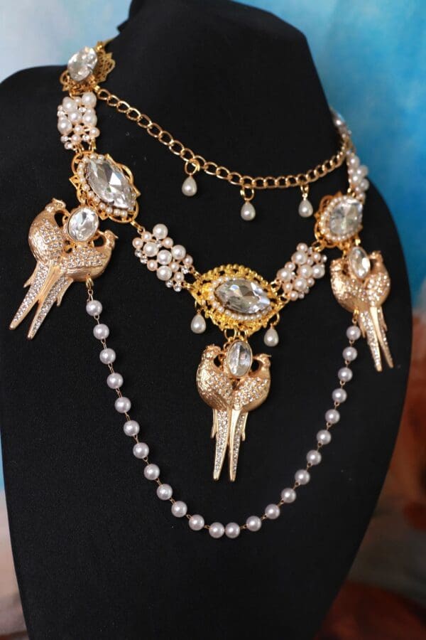 A black mannequin wearing a necklace with pearls and gold.