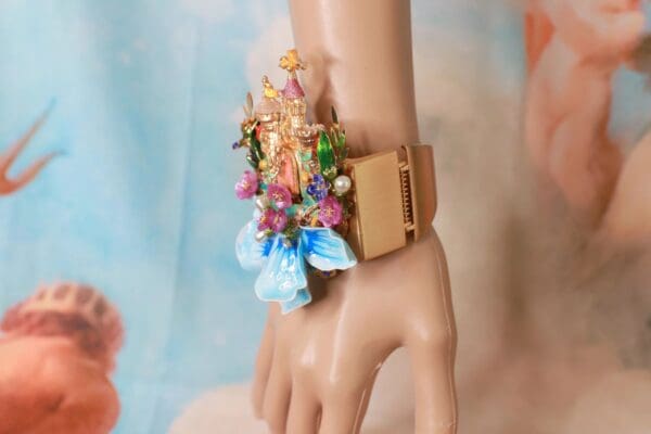 A doll 's arm with a bracelet and flowers on it.
