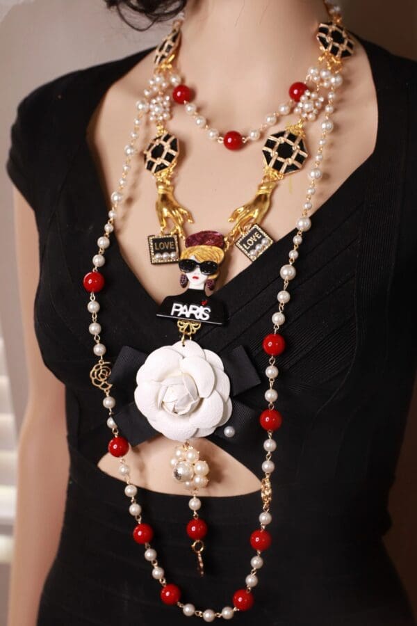 A woman wearing a necklace with pearls and charms.