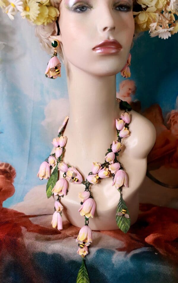 A bust of a woman wearing pink and green jewelry.