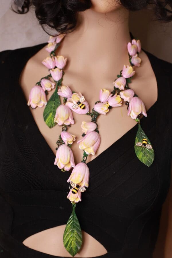A woman wearing a necklace with pink flowers.