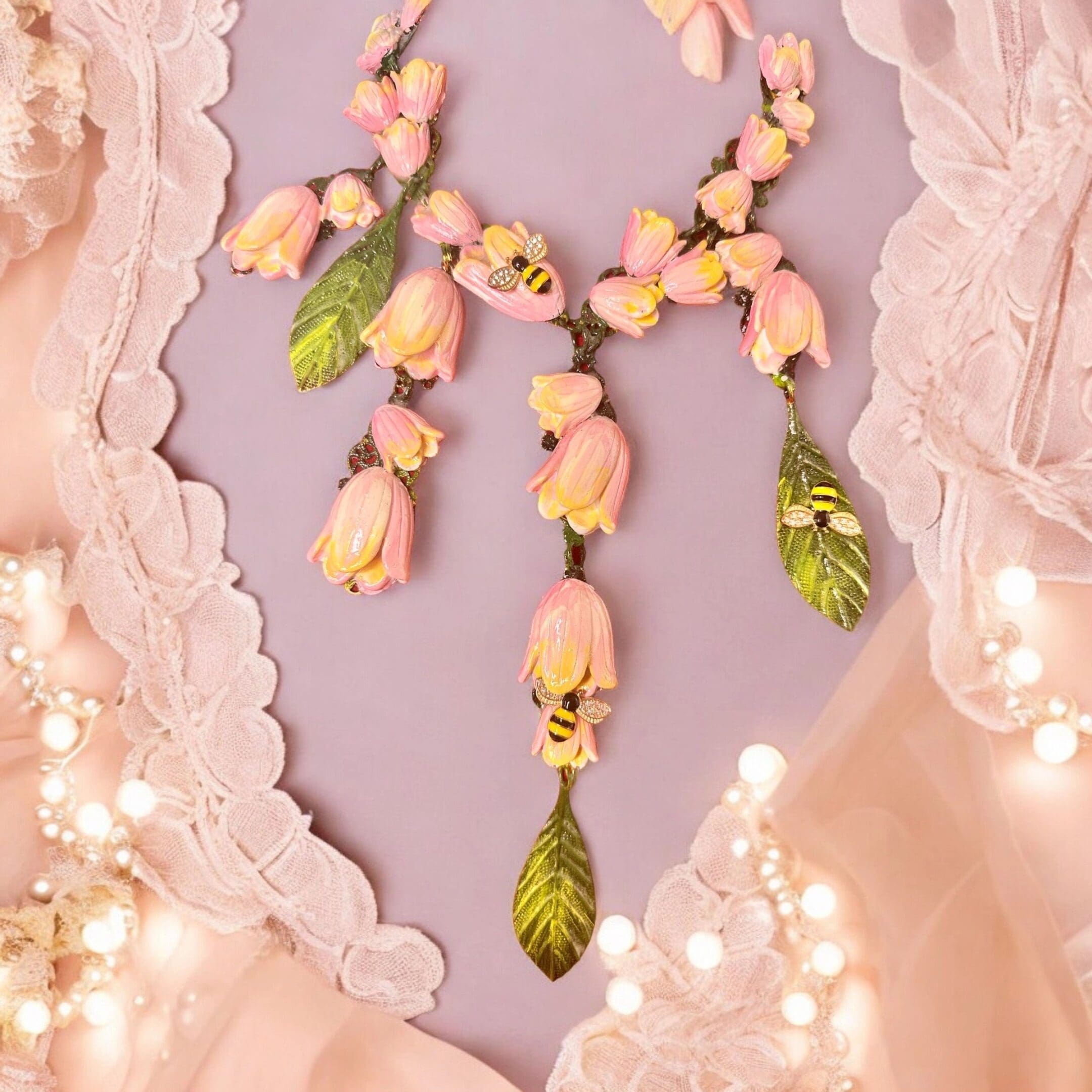 A necklace with pink flowers and green leaves.