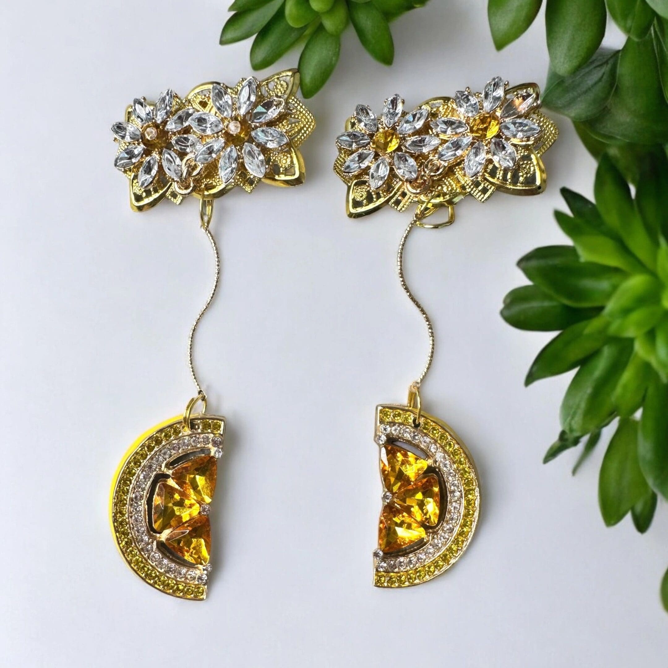 A pair of earrings with gold and yellow stones.