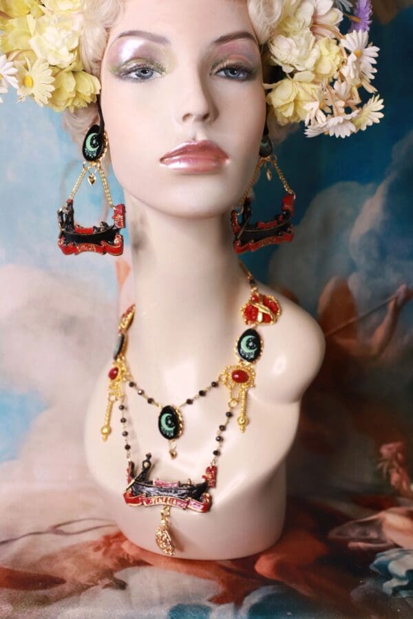 A mannequin wearing jewelry and earrings in front of a painting.